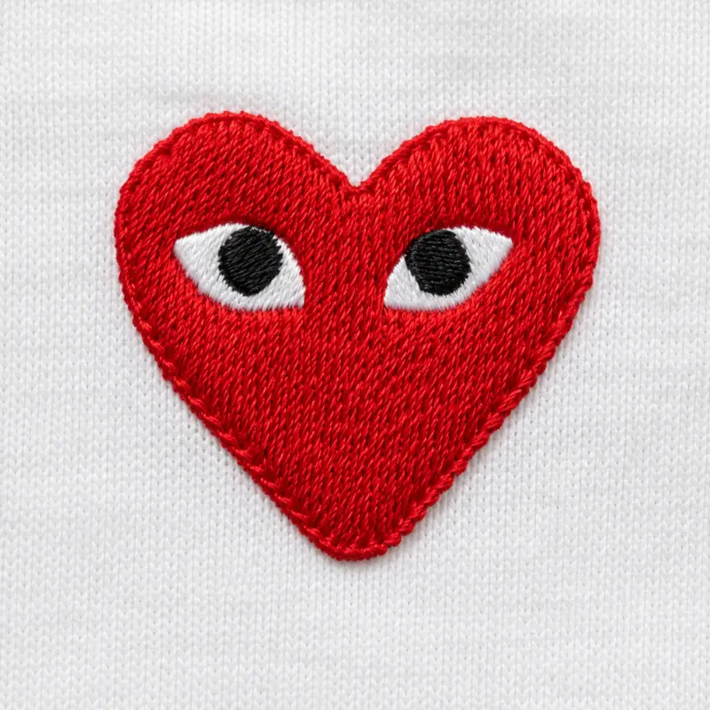CDG Play red heart embroidery macro close-up with slightly irregular eyes on white cotton